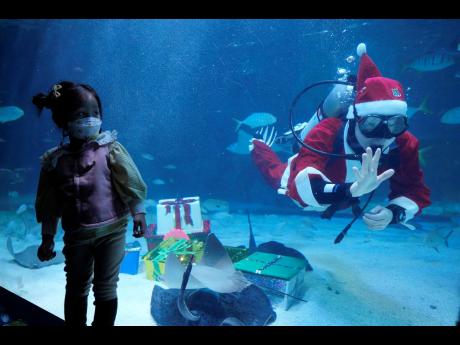 A girl watches a diver clad in a Santa Claus outfit during an event to promote Christmas holiday at the Coex Aquarium in Seoul, South Korea.