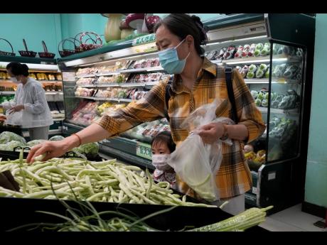 Residents wearing masks shop at a supermarket in the Chaoyang district of Beijing on April 25, 2022. Food companies making big profits as inflation has surged should face windfall taxes to help cut global inequality, anti-poverty group Oxfam said on Monday