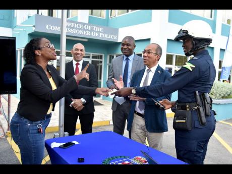 Credit: Kenyon Hemans/Photographer An animated Carlette DeLeon, managing director of Breakthrough Communications, receives a machine-generated demo ticket from Constable Morata Murdock at the Office of the Commissioner of Police on Old Hope Road, St Andrew, Thursday. They were joined by (fr
