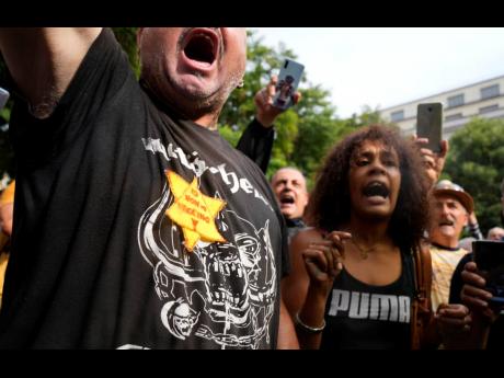 In this July 2021 photo, people stage a protest against the ‘green pass’ in Milan, Italy. Protesters in Italy and France have been wearing yellow Stars of David, like the ones Nazis required Jews to wear to identify themselves during the Holocaust. Som