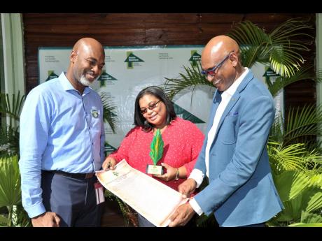 Azalee Lawson (centre), JPS manager for environment, health and safety, and Joseph Williams (right), JPS senior vice- president for generation, read the citation in honour of JPS as Corporate Forest Hero. The Corporate Forest Hero Award and citation were p