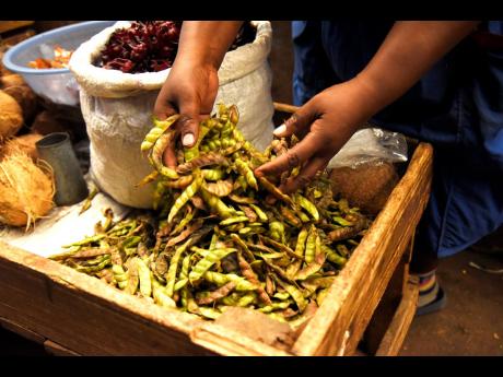 Credit: Nicholas Nunes/Photographer A vendor sorts gungo peas at her stall in Coronation Market in downtown Kingston.