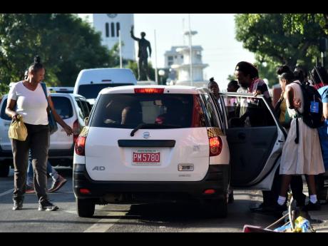 Credit: Kenyon Hemans/Photographer Commuters board a taxicab in downtown Kingston Monday. The Corporate Area was spared the impact of a taxi strike.