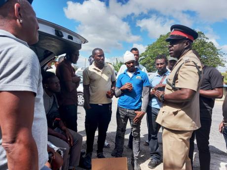 Credit: Photo by Tamara Bailey Sub-officer in charge of the Christiana Police Station, Inspector Valdin Amos, maintaining order among taxi operators who peacefully protested the stipulations of the new Road Traffic Act on Monday.