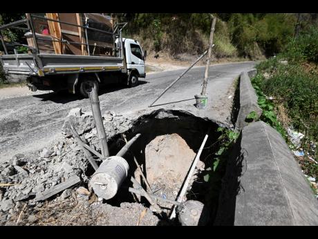 A truck drives past a breakaway section on the Junction main road in the community of Rose Mount, St Andrew.