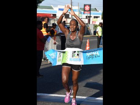 Past winner Jozanne Harris is the first woman to cross the finish line in the Sagicor Sigma 25th Legacy Run Sunday.