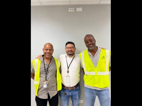 Credit: Contributed COO Carlos Cabrera (centre) shares a photo with Kaneil McKenzie (left) and Anthony Davis (right) hours ahead of their departure to Nigeria.