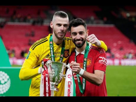 Manchester United’s Bruno Fernandes (right)  and goalkeeper David de Gea pose with the trophy after the English League Cup final between Manchester United and Newcastle United at Wembley Stadium in London yesterday. Manchester United won 2-0.