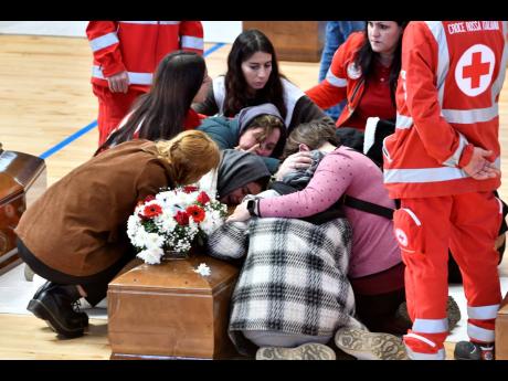 Credit: Giuseppe Pipita Relatives cry on the coffin of one of the victims of last Sunday’s shipwreck at the local sports hall in Crotone, southern Italy, yesterday.