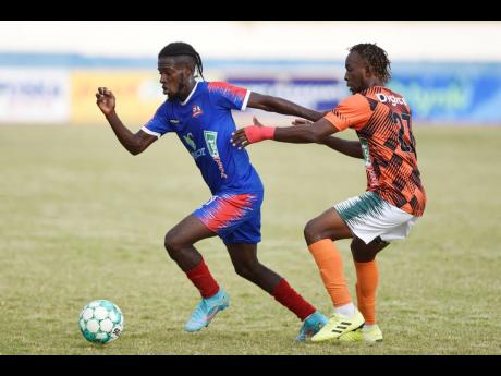 Tkiven Garnett of Tivoli Gardens (right) tackles Shakeen Powell of  Dunbeholden during their Jamaica Premier League match at Ashenheim Stadium, Jamaica College  yesterday. Dunbeholden won 4-1. 