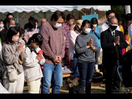 People pause for a minute of silence to commemorate the disaster following an earthquake and tsunami in the Tohoku region 12 year ago, during an anniversary event at Hibiya Park in Tokyo.