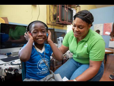 Zahyr Walker, a student at Shrewsbury Early Childhood Institution in St Elizabeth, is happy to have his hearing tested by Sagicor Life Practical Nurse Latoya Johnson, as part of the Sagicor Foundation’s annual Adopt-A-School Health Tour. The students als