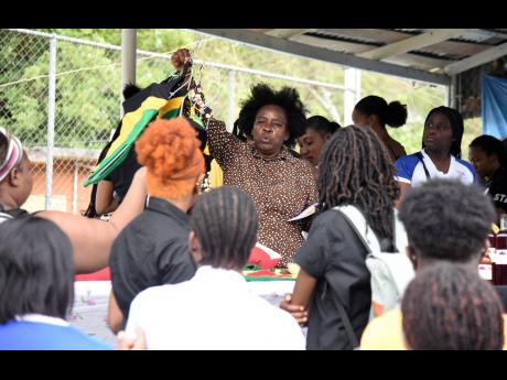 Dorothy Pryce-Maitland (centre) from African Gardens in August Town in St Andrew shows off clothing made in the community to staff and students of The University of the West Indies, Mona, during a tour of the community last Thursday.