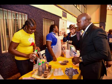 Minister of Agriculture and Fisheries Pearnel Charles Jr samples coffee cane juice while visiting the Rural Agricultural Development Authority display area, during Tuesday’s (March 14) ‘Farmers’ Trade Day’ expo. The event was held inside the Alfred