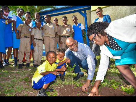 Principal Director of the Meteorological Service of Jamaica, Evan Thompson, plants a soursop tree to commemorate the International Day of Forests at the Constant Spring Primary and Infant School on Tuesday. He is assisted by (from left) Nathaniel Campbell,