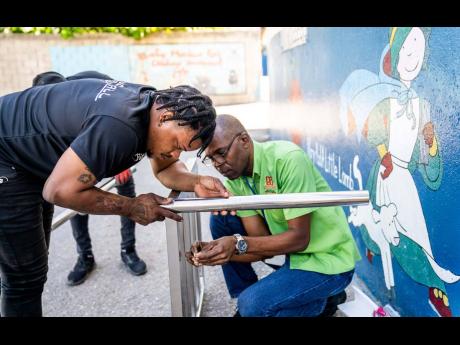Skyfall Events team member Jarvis Vassell (left) and D&G Foundation Accountant Dennis Beckford, are hard at work as they assemble the commercial stove before the official handover.