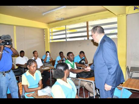 Minister of Transport and Mining, Audley Shaw, interacts with students of Little London High School in Westmoreland as they prepare to sit the road code test administered by the Road Safety Unit and the Island Traffic Authority on March 24.