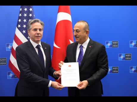 Turkish Foreign Minister Mevlut Cavusoglu (right) hands Finland’s Instrument of Ratification to United States Secretary of State Antony Blinken during a meeting of NATO foreign ministers at NATO headquarters in Brussels yesterday.