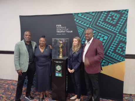 Credit: Daniel Wheeler From left: National senior womens head coach, Lorne Donaldson, Sports Minister Olivia Grange, Sarah Gandoin, FIFA representative, and Michael Ricketts, JFF president, pose with the FIFA Women's World Cup trophy during a tour at the Jamaica Pegasus Hotel