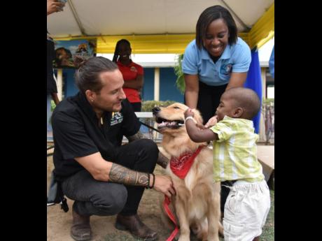 Young Leo Ervin, residential patient at the Bustamante Hospital for Children, pet Teddy Barks. Enjoying the moment are Joseph 'Joey' Brown, curator of the Hope Zoo and Dr Marsha James, ENT consultant at the hospital.  The golden retriever is part of the ch