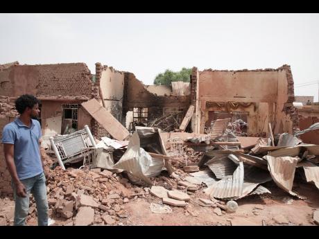 A man walks by a house hit in recent fighting in Khartoum, Sudan, Tuesday, April 25, 2023. Sudan's warring generals have pledged to observe a new three-day truce that was brokered by the United States and Saudi Arabia to try to pull Africa's third-largest 
