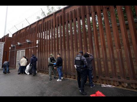 Federal officers remove handcuffs from men before releasing them through a gate in a border wall to Tijuana, Mexico, Wednesday, March 15, 2023, in San Diego. The Biden administration will open migration centres in South and Central America for asylum seeke