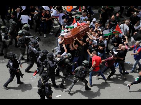 Israeli police clash with mourners as they carry the coffin of slain Al Jazeera journalist Shireen Abu Akleh during her funeral in east Jerusalem, on May 13, 2022. Abu Akleh, a Palestinian-American reporter who covered the Middle East conflict for more tha