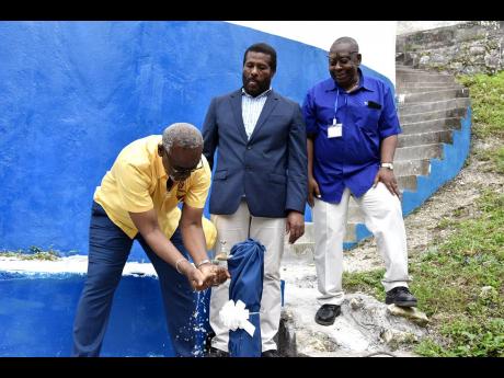 Credit: Herbert McKenis Desmond McKenzie, minister of local government and rural development prepares to drink water from a standpipe attached to the Ashton Catchment tank in Westmoreland on April 27. Looking from left are Daniel Lawrence, member of parliament for Westmoreland Ea