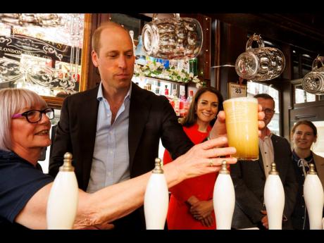 Britain’s Prince William pulls the first pint of Kingmaker, a new brew celebrating the coronation of King Charles III, as he and the Princess of Wales visit the Dog & Duck pub in London, Thursday, to hear how it’s preparing for the coronation of King C