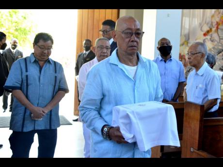 Credit: Kenyon Hemans/Photographer Neil Yap carries the remains of his late mother, Colleen Yvonne Yap, during the funeral for the former mayor of Kingston at the Sts Peter and Paul Roman Catholic Church in St Andrew on Saturday. He was joined by his brothers (left), Kevin Yap and Brian Yap