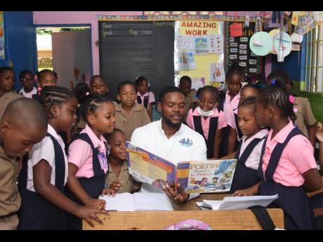 Deputy Mayor of Montego Bay Richard Vernon reads to grade one students from Corinaldi Avenue Primary School for Read Across Jamaica Day on Wednesday.