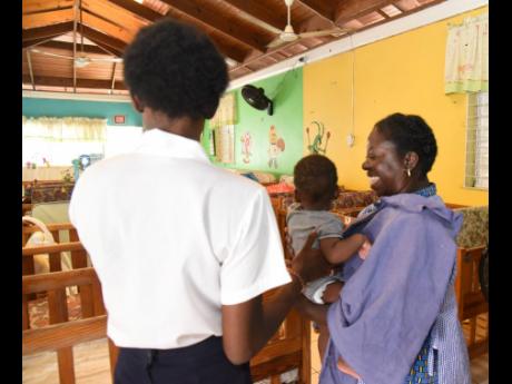 A young mother gets help with her child from a caregiver at the Women’s Centre