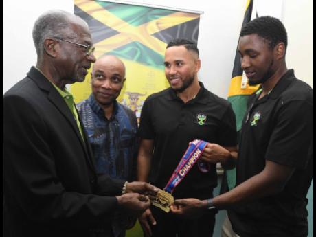 Credit: File (From left) Jamaica Ice Hockey Federation president Don Anderson, Jamaica Olympic Association president, Christopher Samuda, and Jamaica men’s ice hockey team co-captains Jaden Lindo and Teegan Moore admire one of the players’ gold medals that was won