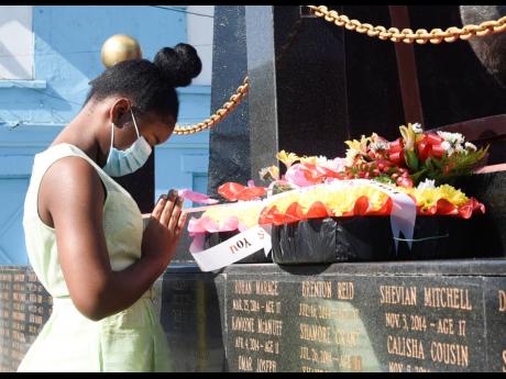 In this 2021 Reajean Bennett, 17, acting youth mayor of Kingston and student of St Hugh’s High School for Girls, bows her head in prayer at the Secret Gardens monument at the intersection of Tower and Church streets in downtown Kingston.