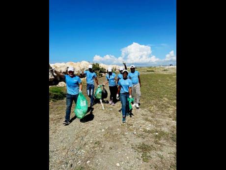 Managing Director of Carreras Limited Franklin Murillo and 2022 Carreras Seek Scholarship recipients collect debris along the Palisadoes strip.
