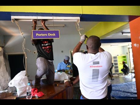 Members of the VM team replace a lighting fixture inside the Kingston and St Andrew Parish Library’s Junior Library.