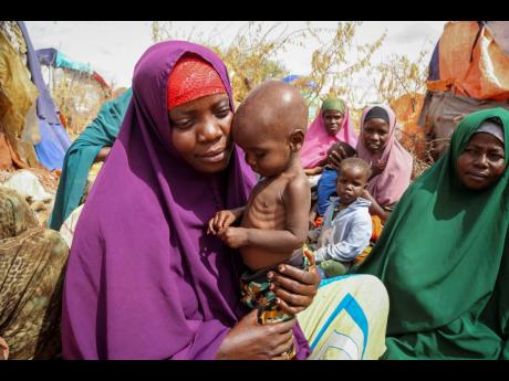 Nunay Mohamed, 25, who fled the drought-stricken Lower Shabelle area, holds her one-year old malnourished child at a makeshift camp for the displaced on the outskirts of Mogadishu, Somalia, on June 30, 2022. 