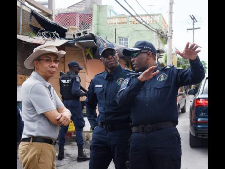 Credit: Ashley Anguin Vernon Ellis (right), Senior Superintendent of Police (SSP), speaks with national security minister Dr Horace Chang (left) and Clifford Chambers, Assistant Commissioner of Police, during a recent tour of the violence-torn community of Mount Salem in St Ja
