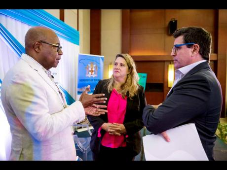 Minister of Tourism Edmund Bartlett (left) engages Inter-American Development Bank (IDB) executives, Operations Lead Specialist Olga Gomez Garcia (centre) and Lorenzo Escondeur, chief of operations, Jamaica. Bartlett and the IDB executives were presenters 