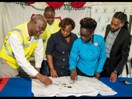 From left: An enthused Courtney Douce, infrastructure manager at the National Education Trust (NET), shows the blueprint of the new block to be built at the Bridgeport High School in St Catherine while Keon Hinds, managing director, N.F. Barnes Constructio