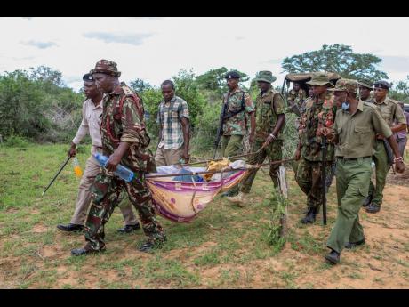 Police and local residents carry the exhumed bodies of victims of a religious cult in southern Kenya on April 23. The number of people who died after a Kenyan pastor ordered his followers to starve to death in order to meet Jesus is at more than 300, autho
