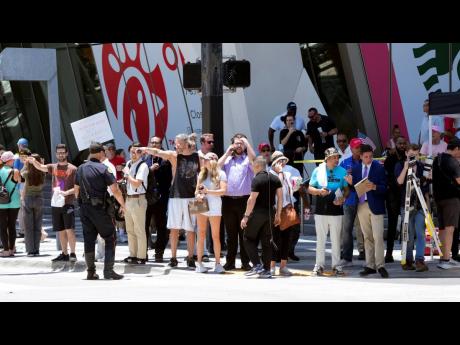 People watch as the motorcade carrying former President Donald Trump arrives at the Wilkie D. Ferguson Jr US Courthouse in Miami yesterday. 