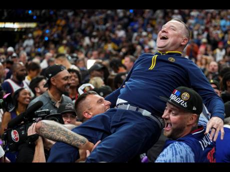 Denver Nuggets head coach Michael Malone is hoisted up by fans after the team won the NBA Championship with a victory over the Miami Heat in Game 5 of basketball’s NBA Finals on Monday, June 12, 2023, in Denver.