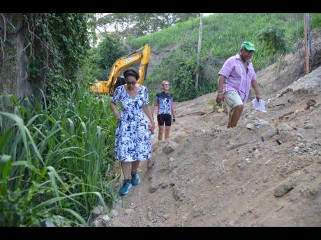 Credit: Kenyon Hemans (From left) Bridgette Azan, Jurgen Von Dueszeln and Errol Williamson, residents of Tavistock Terrace in St Andrew, navigate a section of the road that was blocked after contractors cut another road to a property on the hill and encountered difficulties.