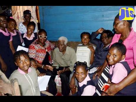 Centenarian Edwin McFarlane (seated) with (from left) Principal of Sudbury Primary and Infant School in St James, Susan Davis; teacher at Sudbury Primary and Infant, Rose Marie Harvey-Smith; guidance counsellor at the school, Althia Palmer; member of the s