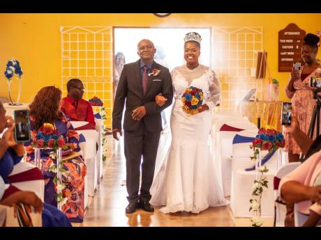 The beautiful bride, alongside her father, Glenval Smith, makes her way up the aisle to say “I do” to her groom.