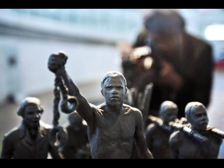 Credit: AP/ File A man photographs a maquette of a statue, at City Hall, London, in this 2008 photo, which now stands as a permanent slavery memorial.