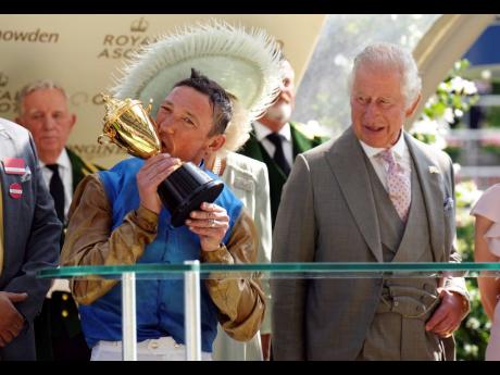 Credit: AP Jockey Frankie Dettori celebrates with the Gold Cup after riding Courage Mon Ami to victory as Britain’s King Charles III and Queen Camilla (partly hidden) look on, on day three of Royal Ascot at Ascot Racecourse, in Berkshire, England, yesterday.