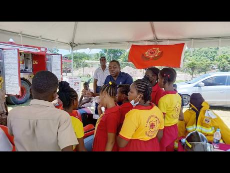 Acting Sergeant Jason Fuller of the fire prevention and public relations unit at the May Pen Fire Station engages students of St Robert Bellarmine Preparatory & Kindergarten School before leading them on a tour of the fire truck.