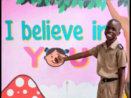 Eleven-year-old Donfarrel Lawrence points to an inspirational sign painted at Corinaldi Avenue Primary School in Montego Bay, St James. Lawrence himself became an inspiration through his transformation and Primary Exit Profile examination by earning a plac